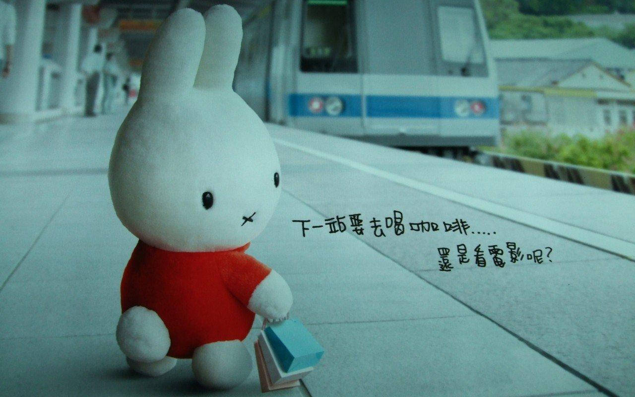 白色兔毛公仔在火車站月台上拿著書。