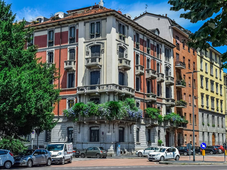 色彩繽紛的歷史公寓建築，設有陽台，汽車停放在陽光明媚的城市街道上。
