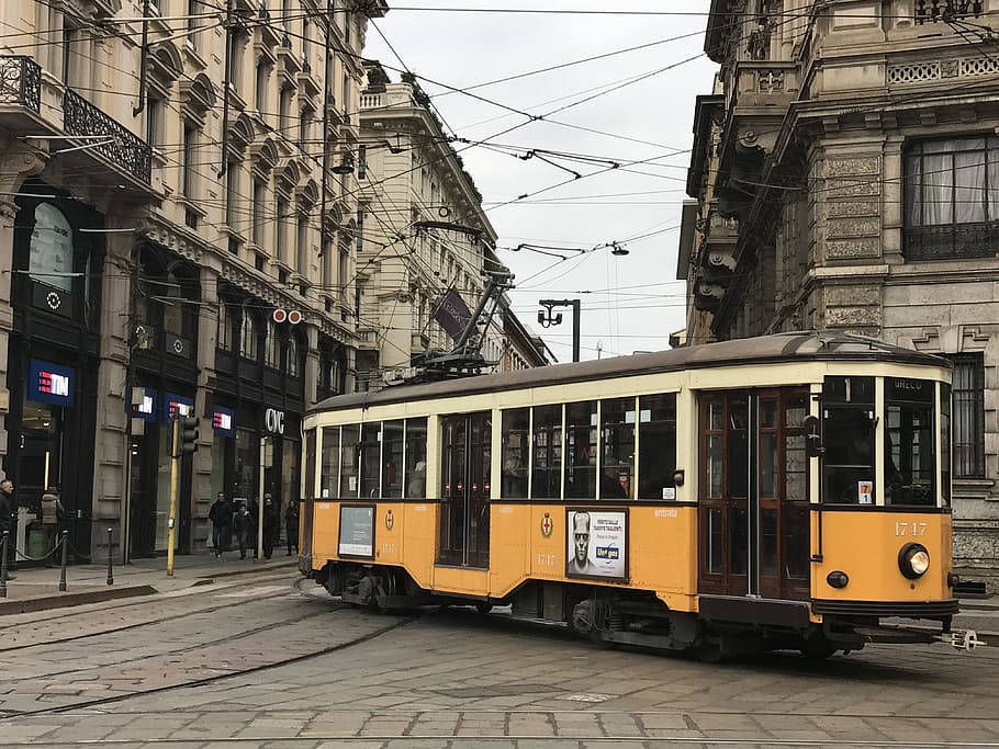 歷史建築之間鵝卵石街道上的復古黃色電車。