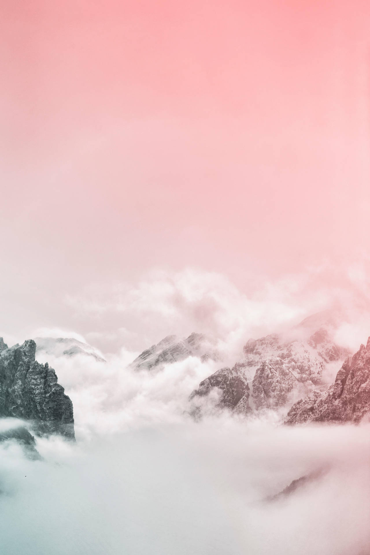 粉紅色的天空和雲朵飄過從霧中浮現的積雪群山。