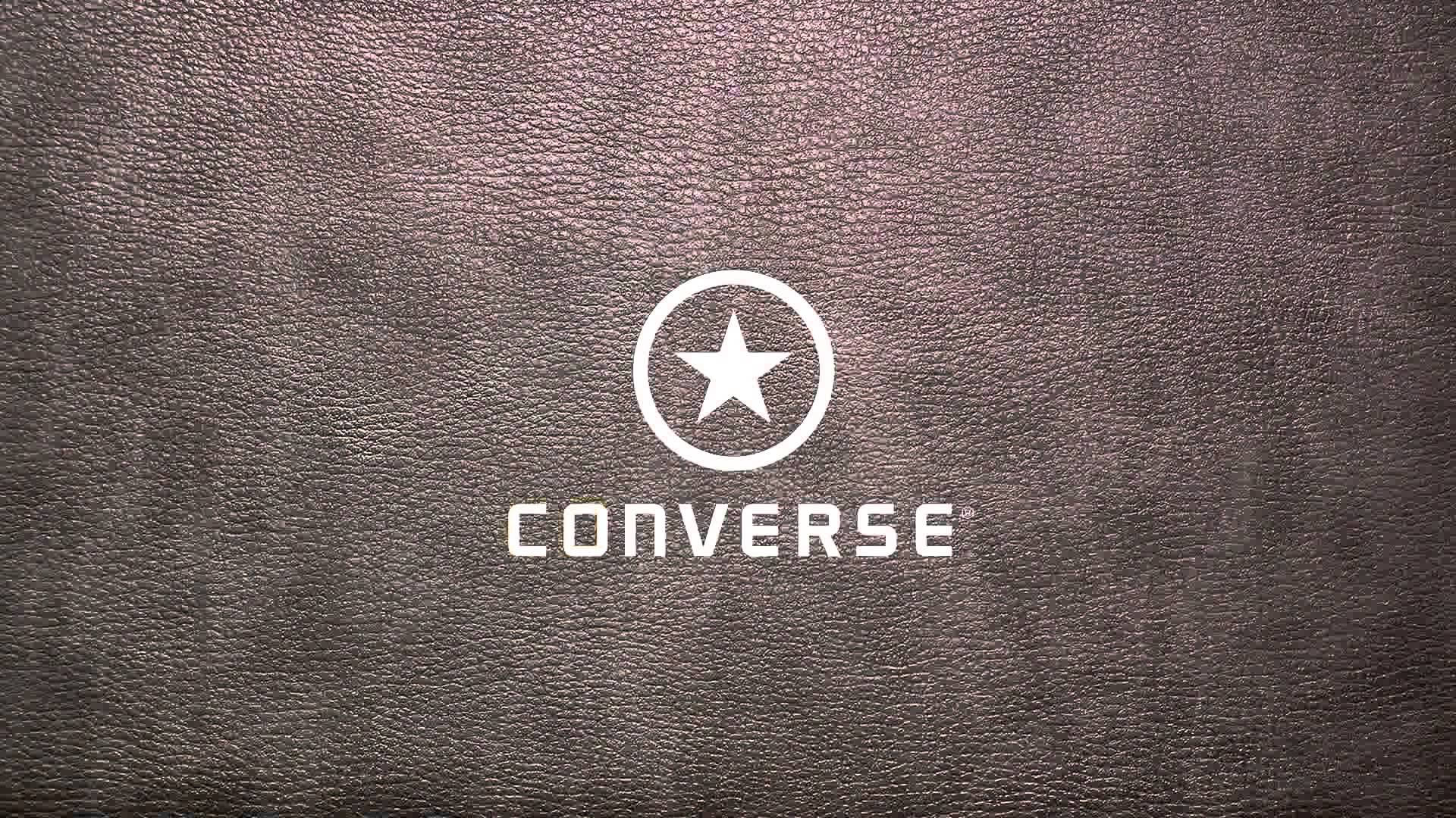 粉灰皮革 Converse 標誌 壁紙 — 白色Converse標誌配星形徽章，居中於紋理深棕色皮革背景上。