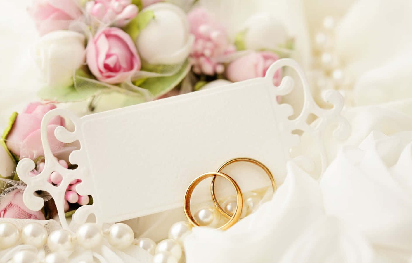 金色結婚戒指放在珍珠上，配以花朵和卡片，適合新娘主題。