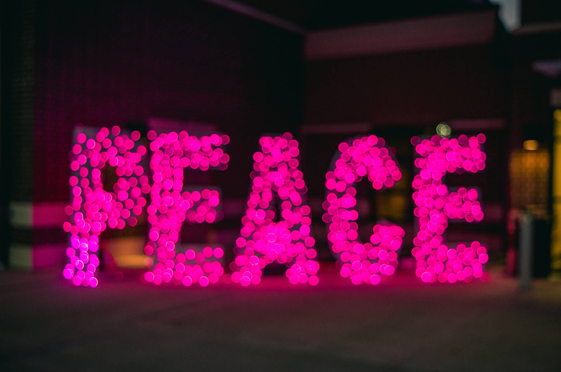 粉紅色燈光在夜間城市環境中拼出PEACE。