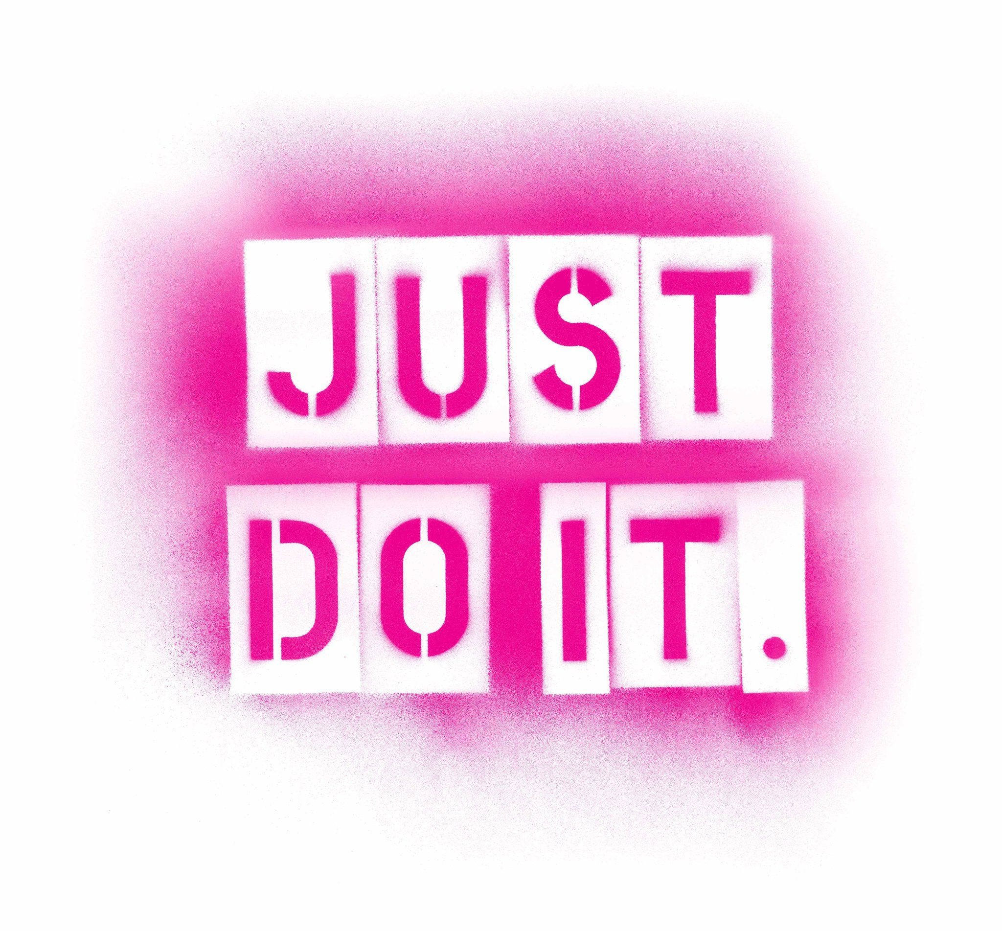 粉紅噴漆風格的「Just Do It」 壁紙 — 大膽的粉紅色噴漆「JUST DO IT」文字，以白色模板呈現，背景為亮白色，帶有柔和粉紅色光暈。
