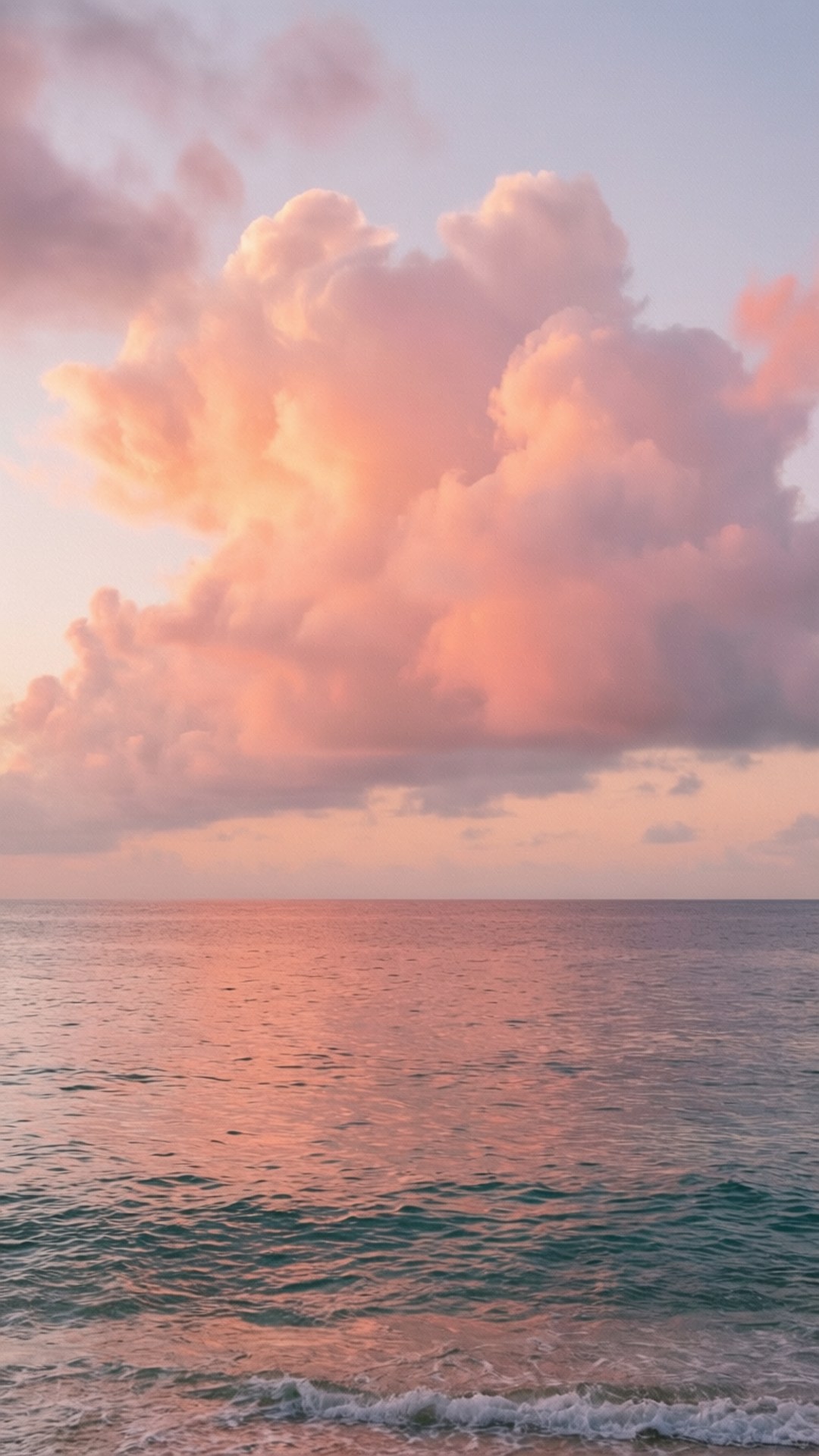 粉紅色和橙色雲彩在日落地平線的平靜海面上反射。