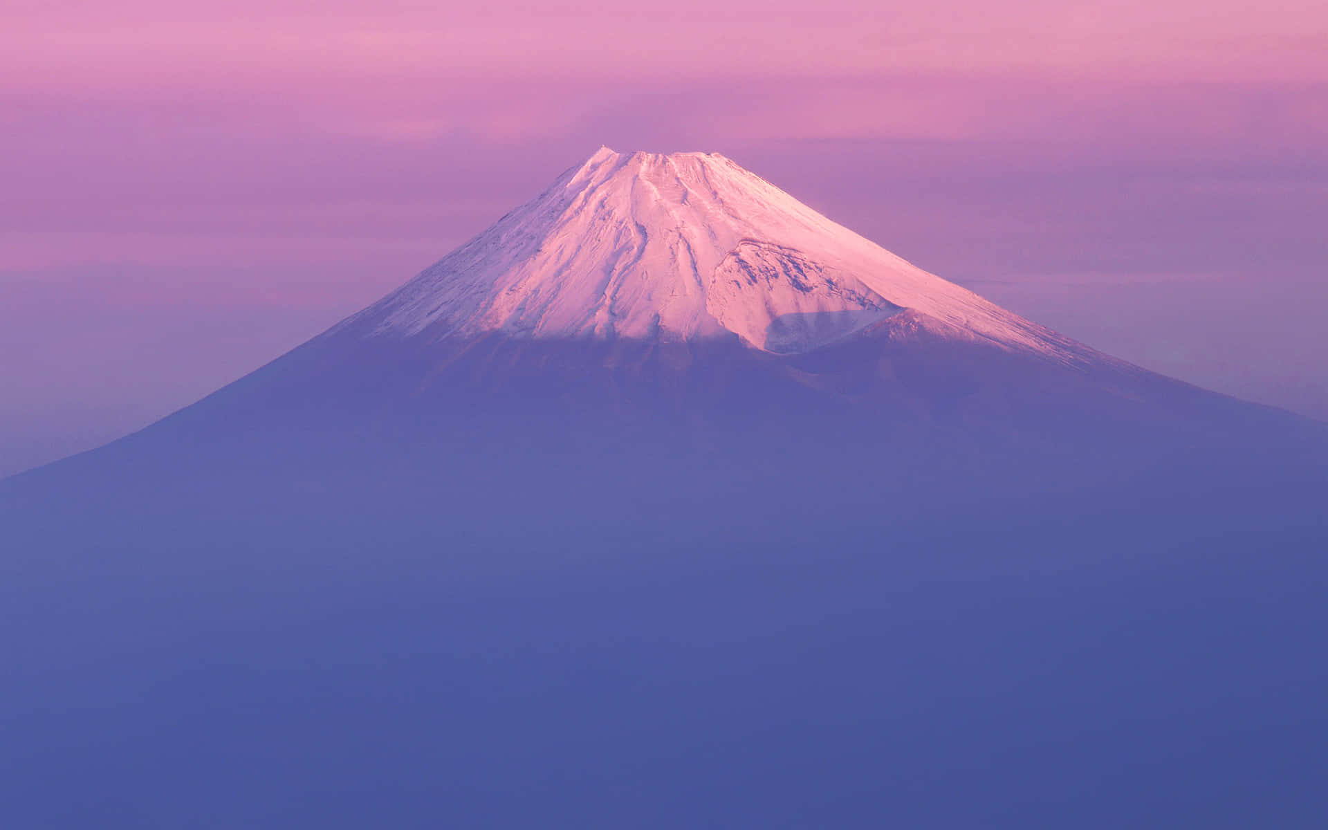 富士山沐浴在粉紅和紫色的暮光中，山頂覆蓋著白雪。