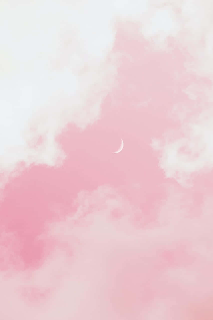 一彎月牙在寧靜的天空中穿過柔軟的粉紅和白色雲朵閃耀。