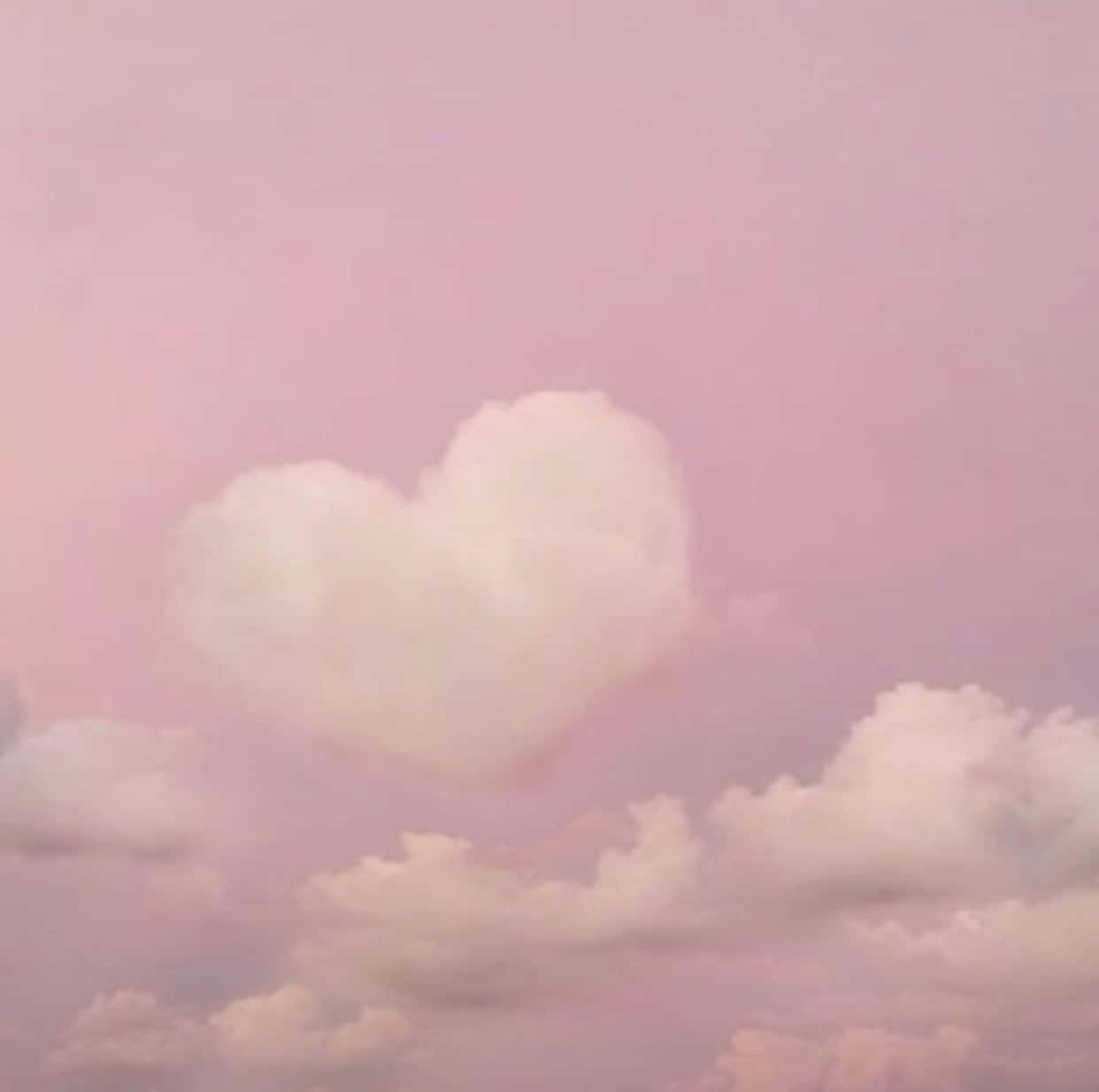 心形雲朵漂浮在粉紅色天空上，伴隨著柔軟的雲朵。