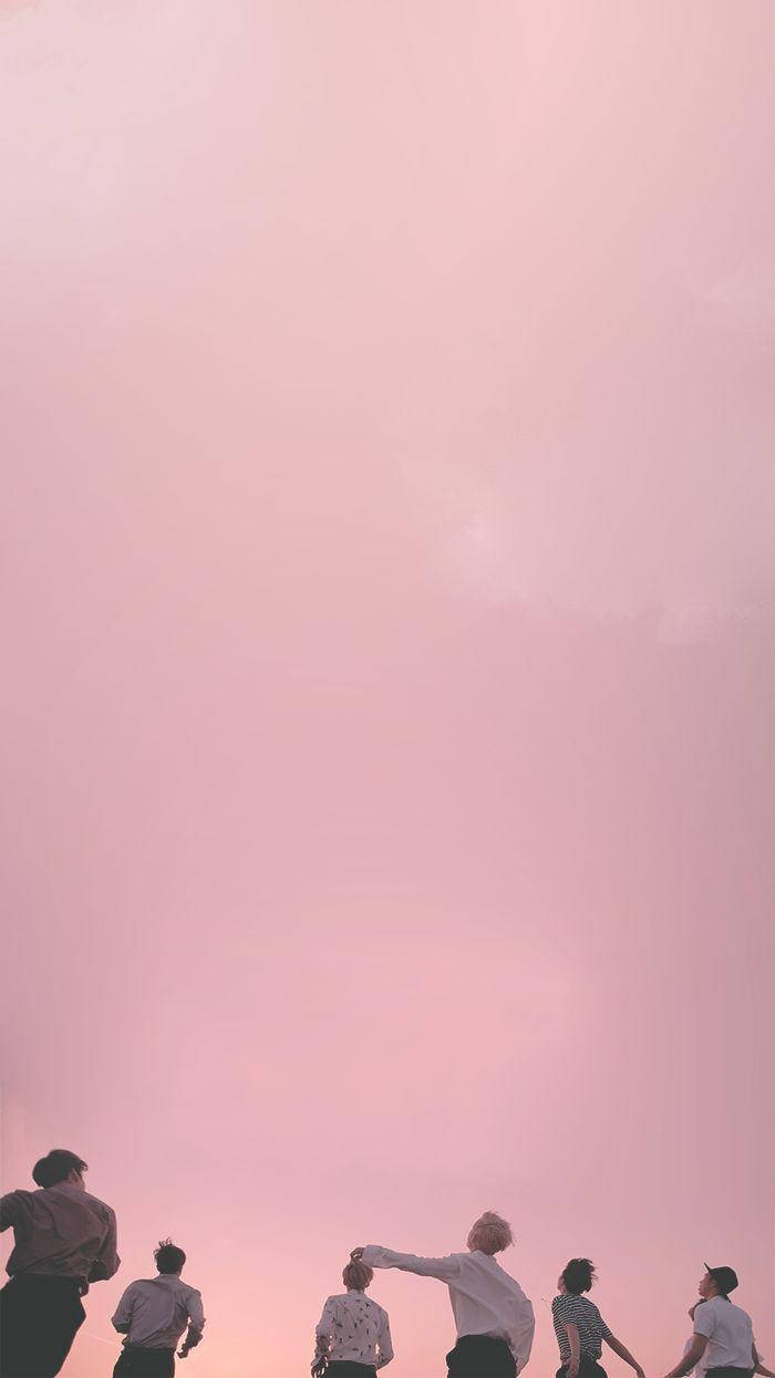 粉紅天空與BTS美學Tumblr 壁紙 — 五個人站在廣闊的粉紅色日落天空下形成剪影，其中一人驚奇地指向天空。