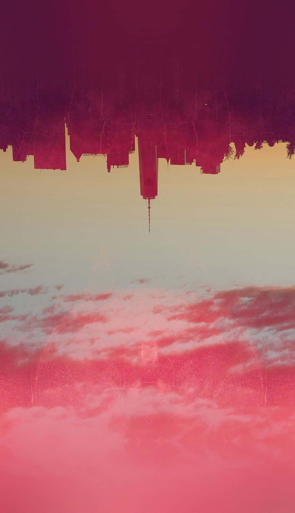 粉紅天空與建築物 壁紙 — 在粉紅色和紫色日落天空下，水中倒映的超現實倒置城市景觀。