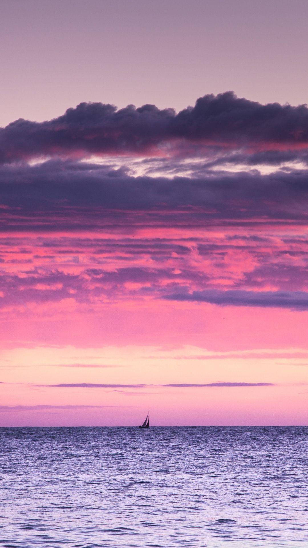 帆船在平靜的海洋上，粉紅紫色黃昏天空