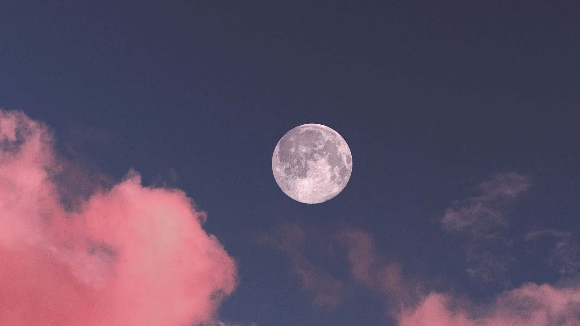滿月在暮色天空中升起於粉紅色雲朵之上。