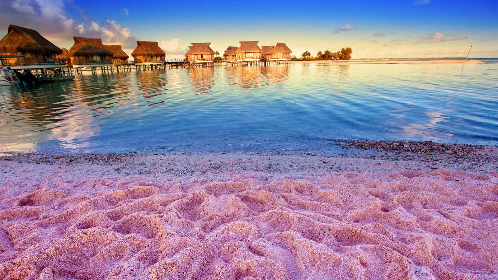Pink Sand Beach 桌布 壁紙 — 粉紅沙灘遇上碧綠潟湖，水上平房在金色日落中。