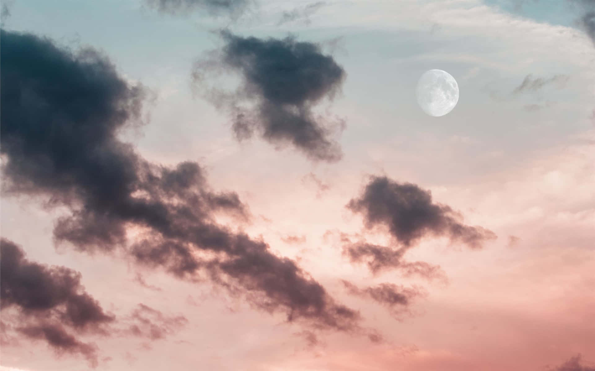 滿月穿過粉紅和青綠色的雲層升起於黃昏。