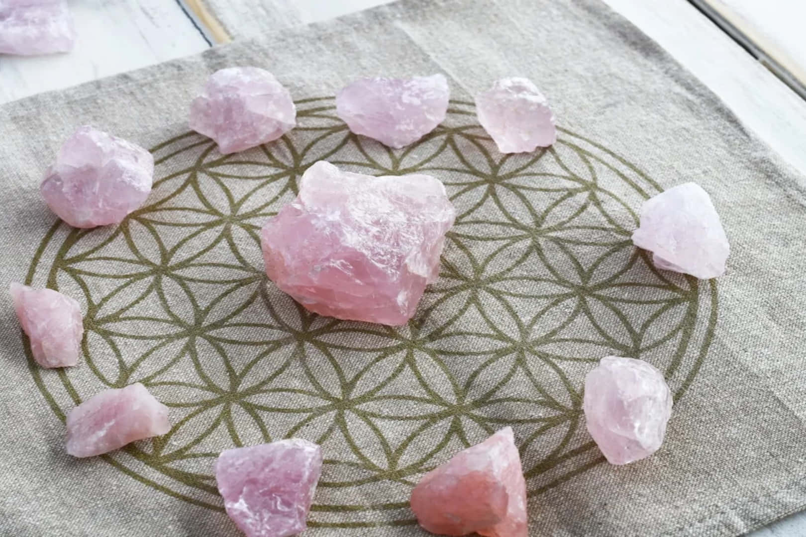Pink Crystal Quartz 桌布 壁紙 — 粉紅玫瑰石英晶體在紋理布上排列成神聖幾何圖案。