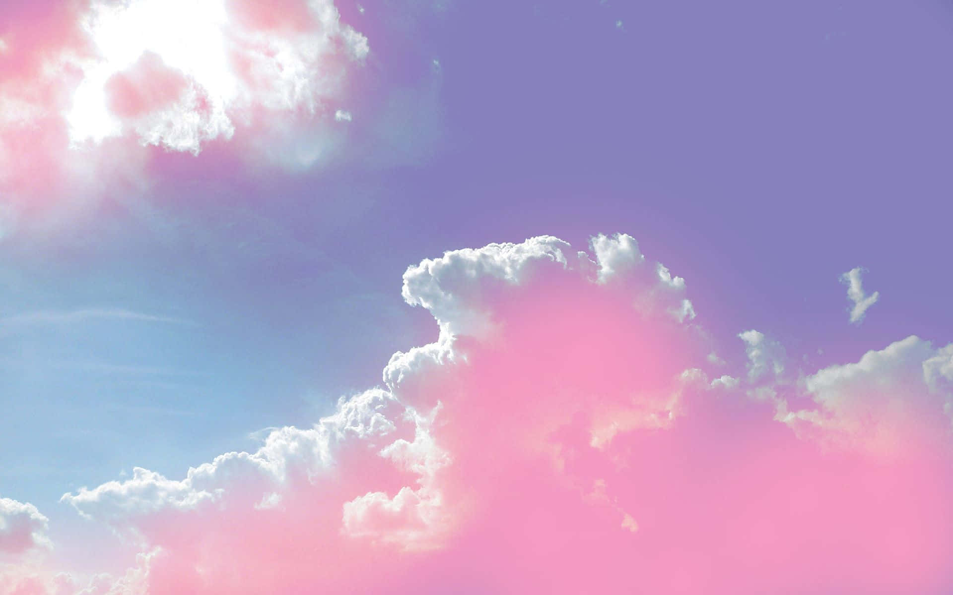 粉紅美學雲景攝影 壁紙 — 夢幻的天空，蓬鬆的白雲沐浴在柔和的粉紅色和紫色色調中，背景是漸變藍色。