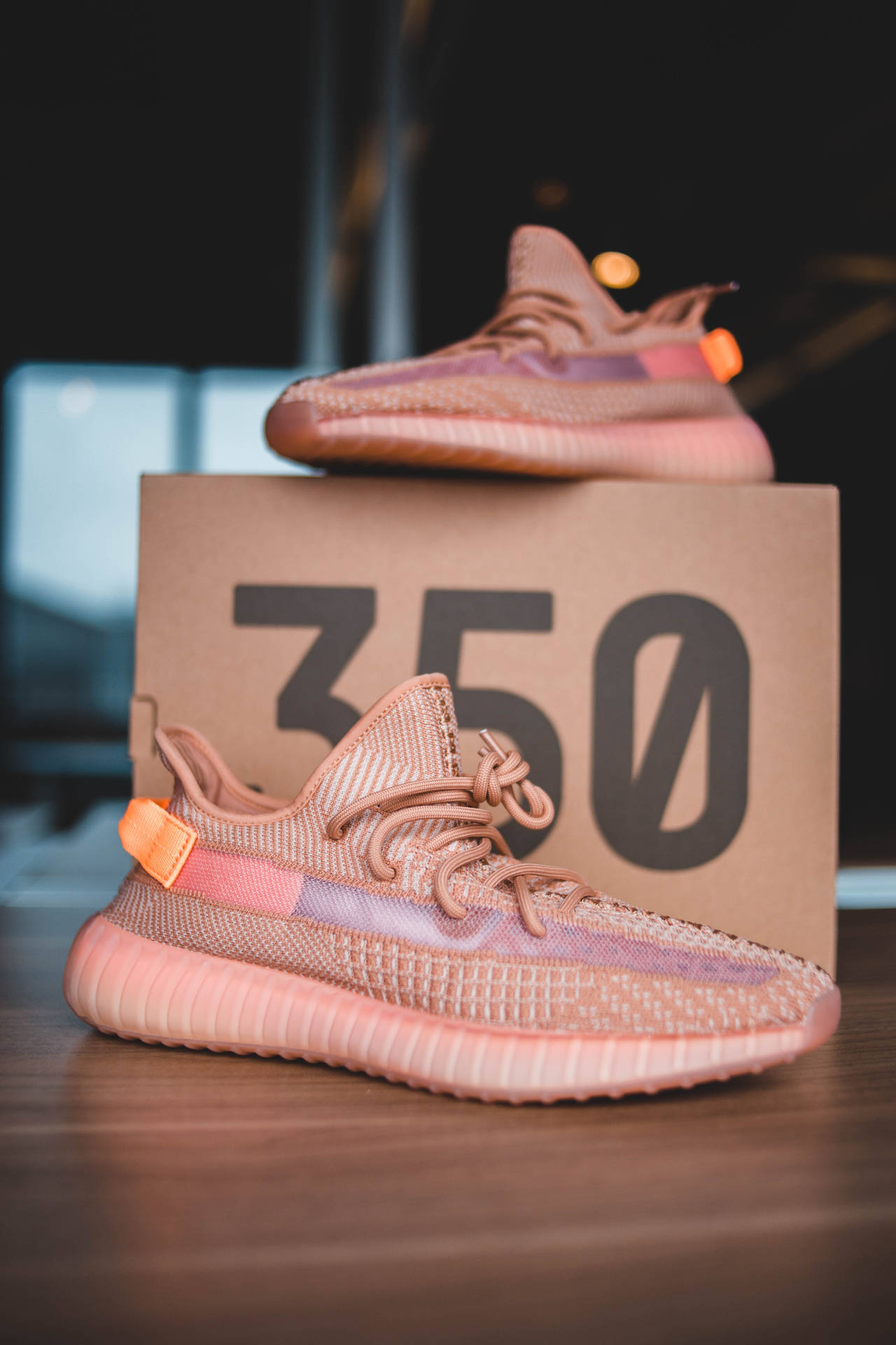 室內粉紅色和橙色的Yeezy Boost 350運動鞋放在盒子上。