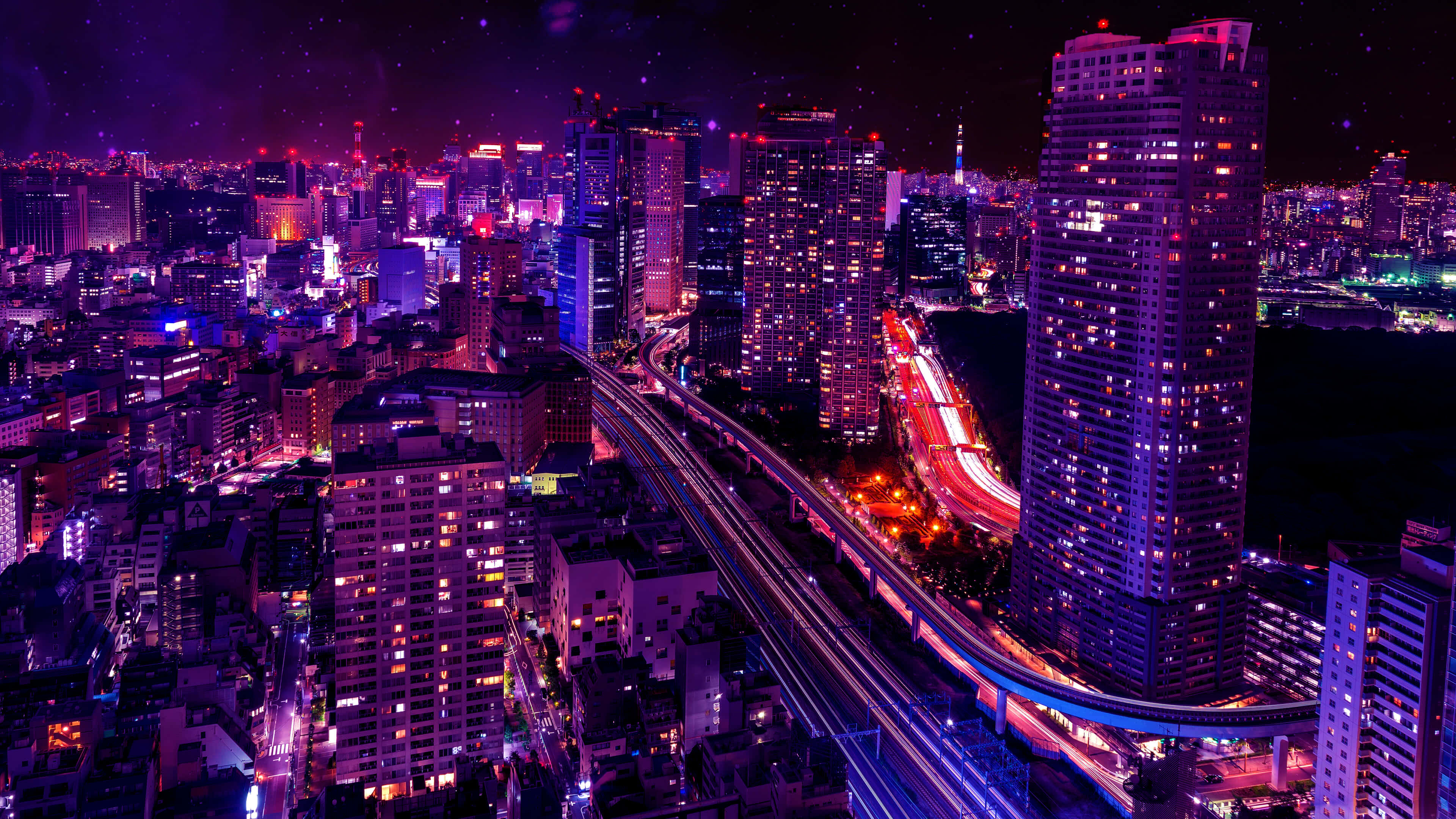 粉紅色城市燈光 壁紙 — 夜晚充滿活力的紫色和藍色霓虹燈城市景觀，發光的摩天大樓和高架道路上的車流光跡。