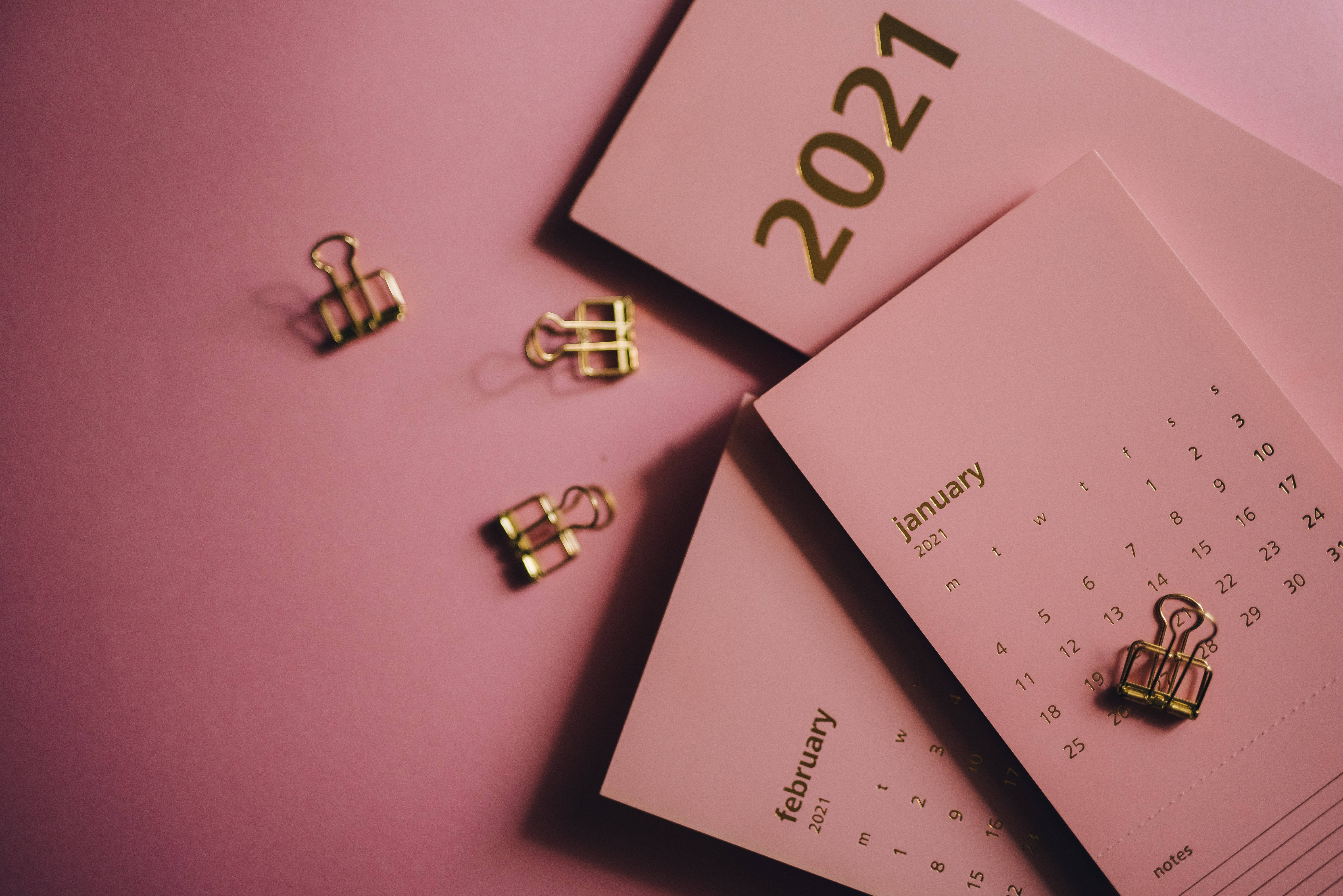 2021 Desktop 桌布 壁紙 — 粉紅色書桌，配有金色活頁夾和顯示一月和二月的2021年日曆頁面。
