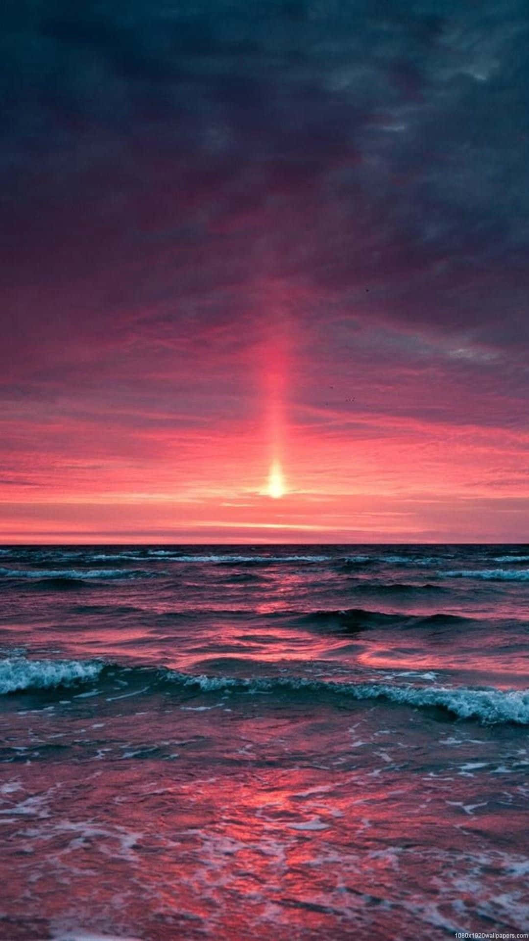 海洋波浪上充滿活力的粉紅色和紫色日落，帶有發光的地平線。