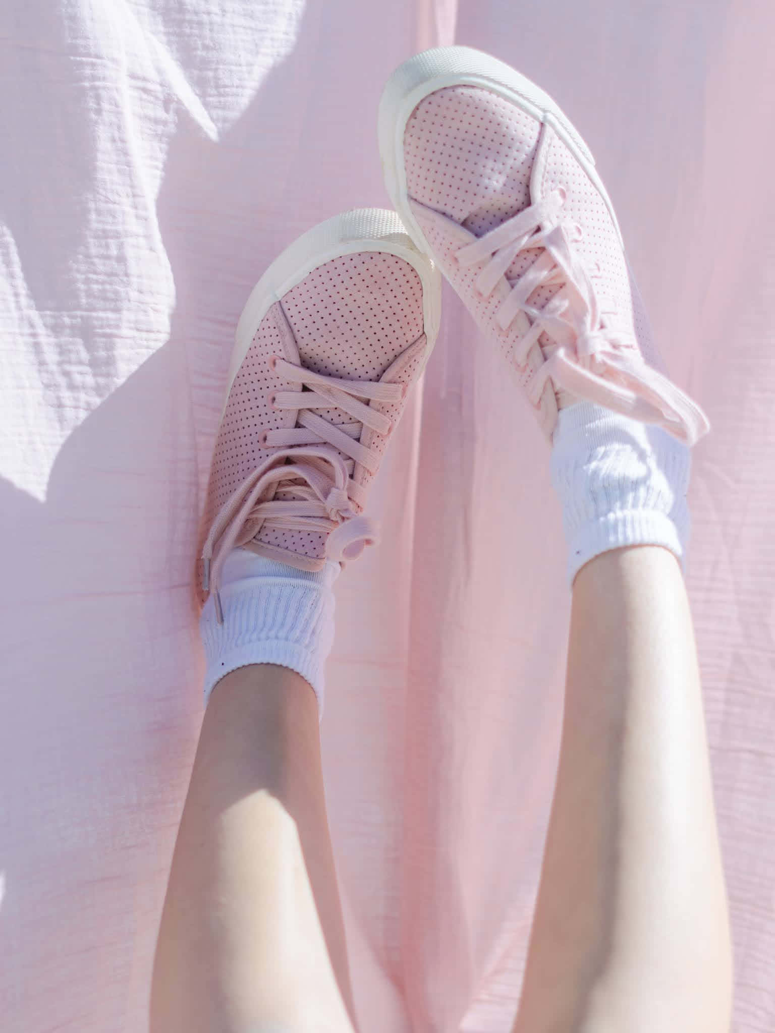Pink Shoes 桌布 壁紙 — 粉紅色運動鞋配白色襪子，在明亮陽光下靠著柔軟的粉紅色布料背景。