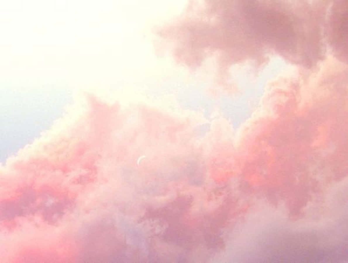粉紅雲朵天空圖 壁紙 — 柔和的粉紅與蜜桃色天空，蓬鬆雲朵部分遮擋著纖細的彎月。