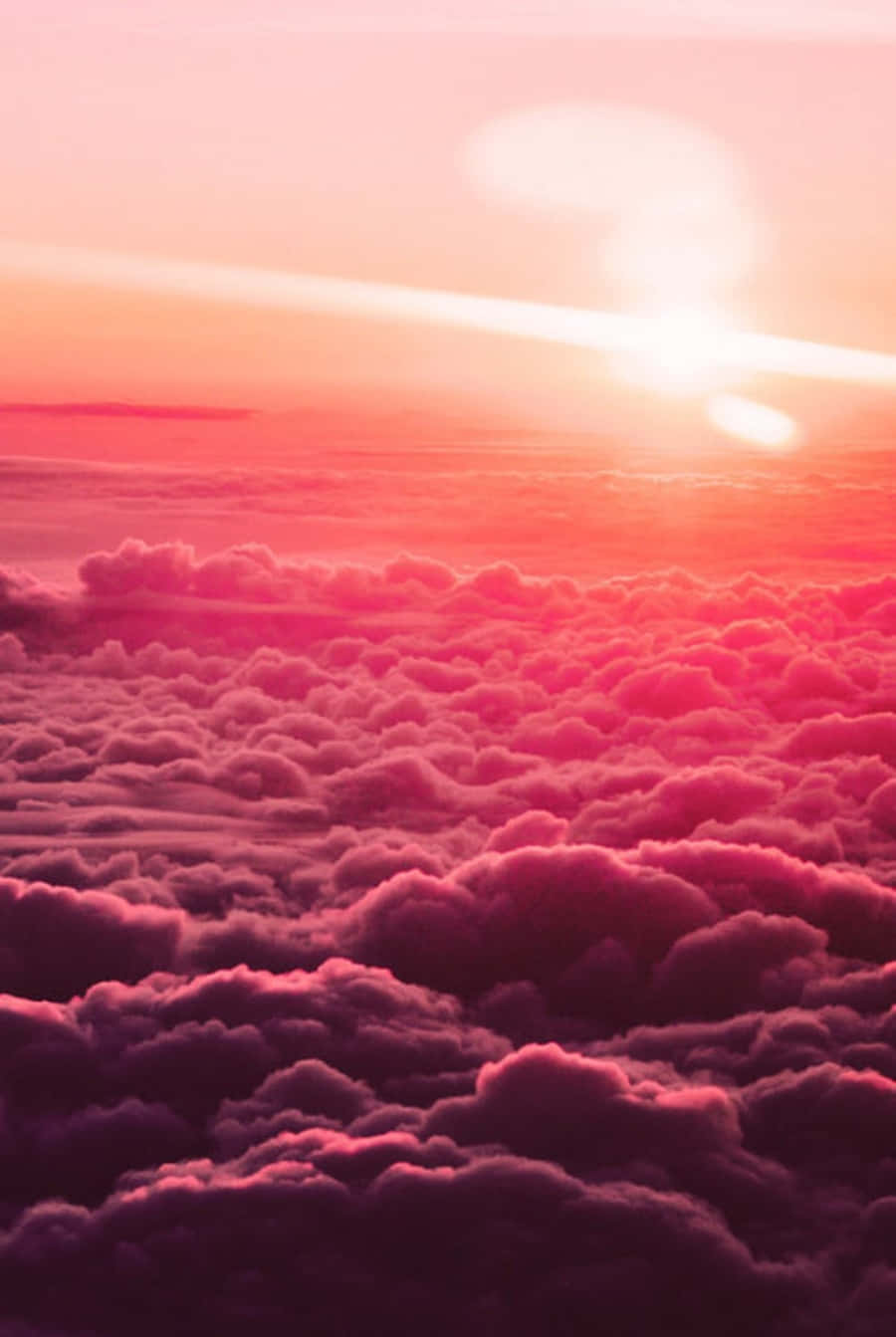 粉紅雲朵肖像畫 壁紙 — 令人嘆為觀止的空中景觀，蓬鬆的雲朵沐浴在鮮豔的粉紅色和橙色色調中，太陽在上方落下。