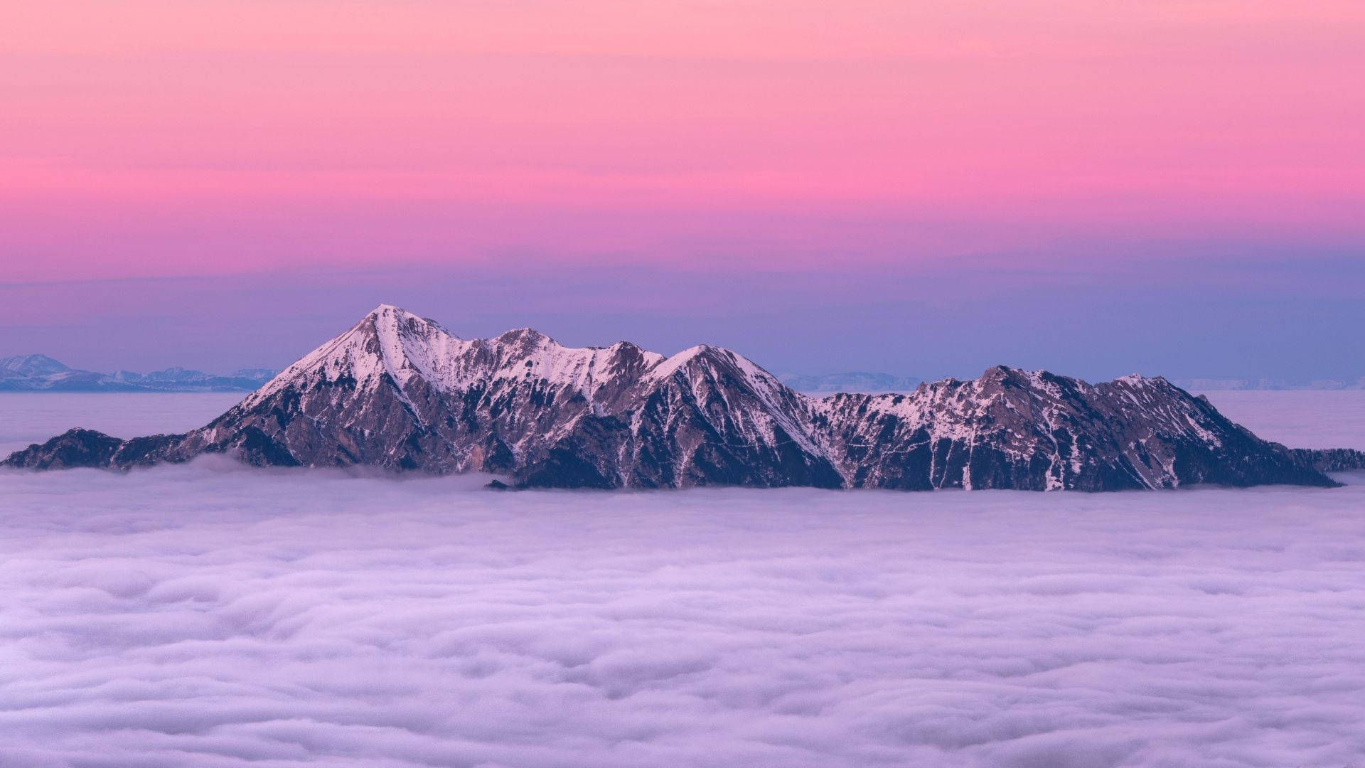 日出時，白雪覆蓋的山峰從雲海中浮現。