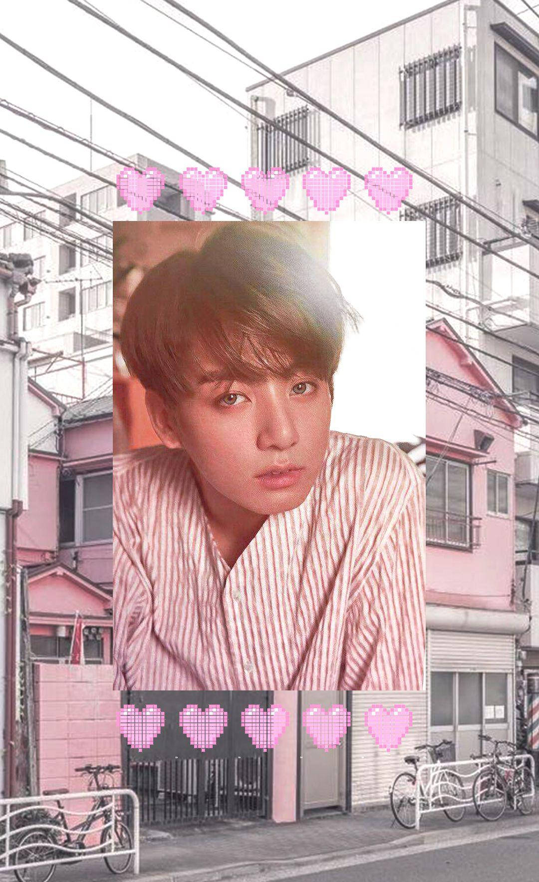 粉紅風 Jungkook 美學壁紙 壁紙 — 一位身穿條紋襯衫的年輕男子位於粉紅色調的城市街道場景中央，像素心形在上方和下方漂浮。
