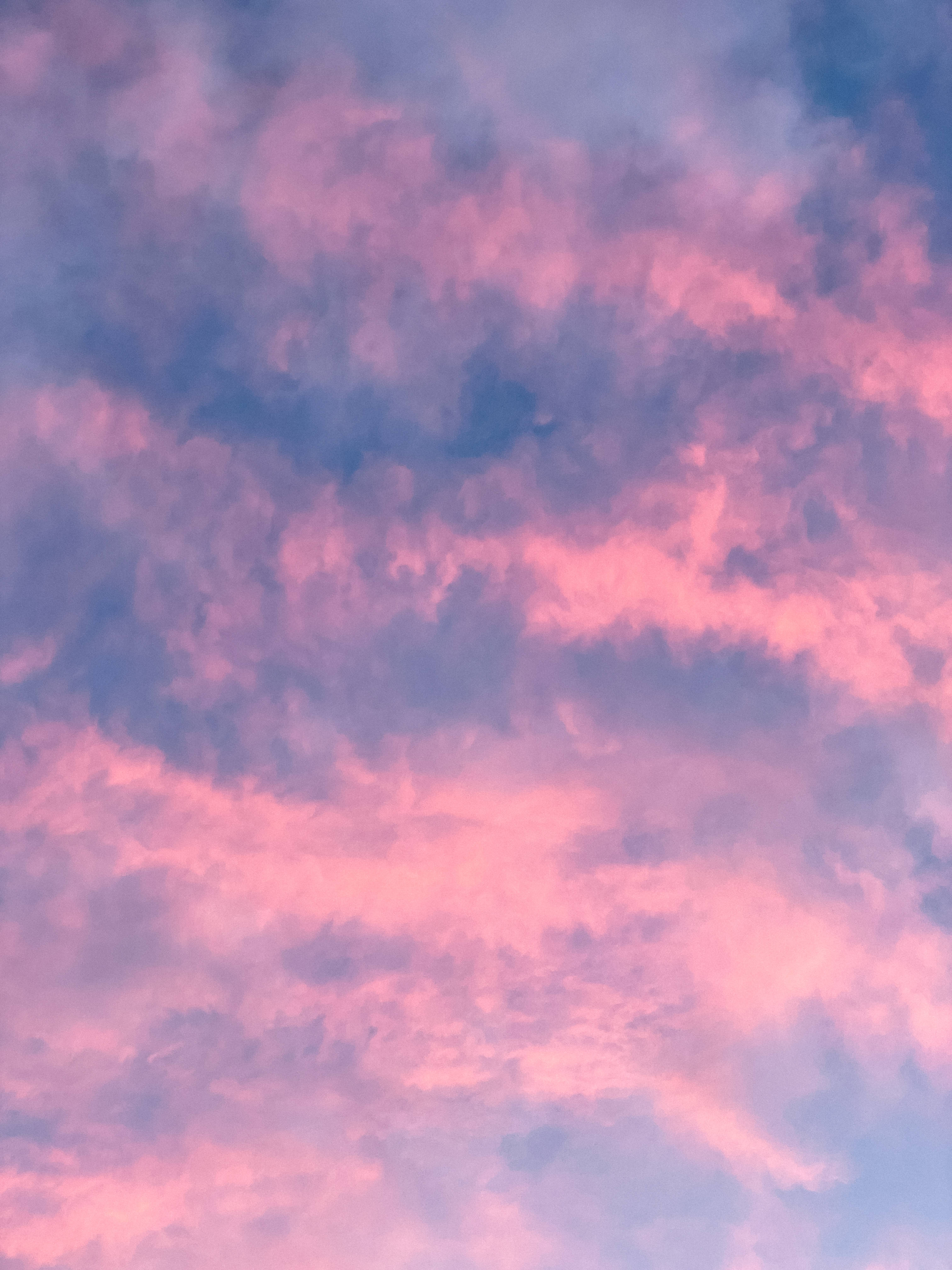 粉紅飄逸雲朵天空美學壁紙 壁紙 — 夢幻般的天空，以柔和的粉紅色和薰衣草色雲彩繪在暮光藍色背景上。