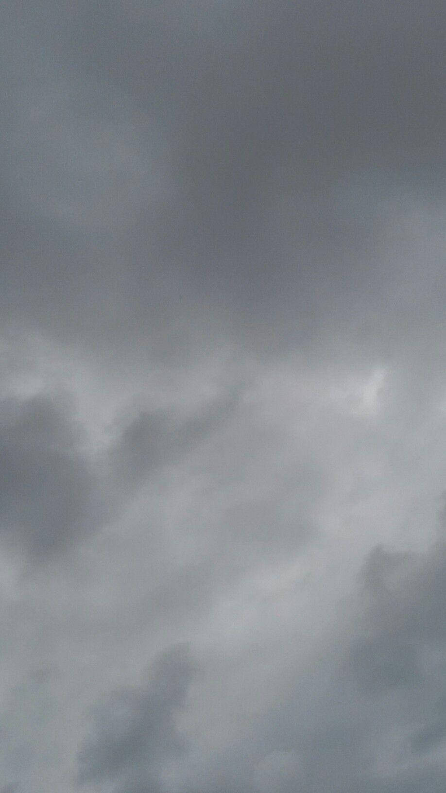 粉紫交融的夢幻光暈 壁紙 — 陰沉的天空佈滿濃密的灰色雲層，遠方有一絲微弱的光線穿透而出。