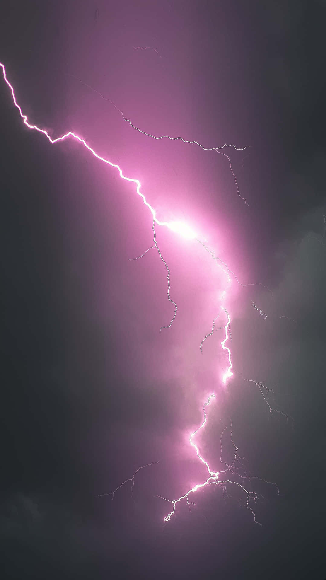 一道強勁的粉紅色閃電照亮了黑暗的暴風雨天空。