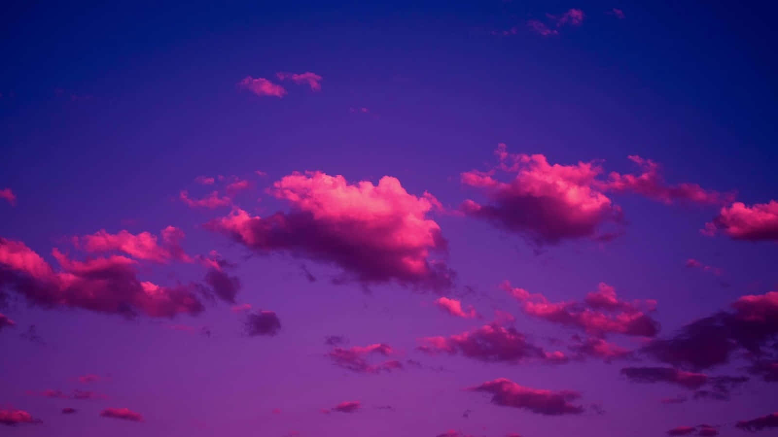 粉紫雲朵畫 壁紙 — 鮮豔的粉紅雲朵在深紫色的暮色天空中飄移，營造出超現實且夢幻的氛圍。