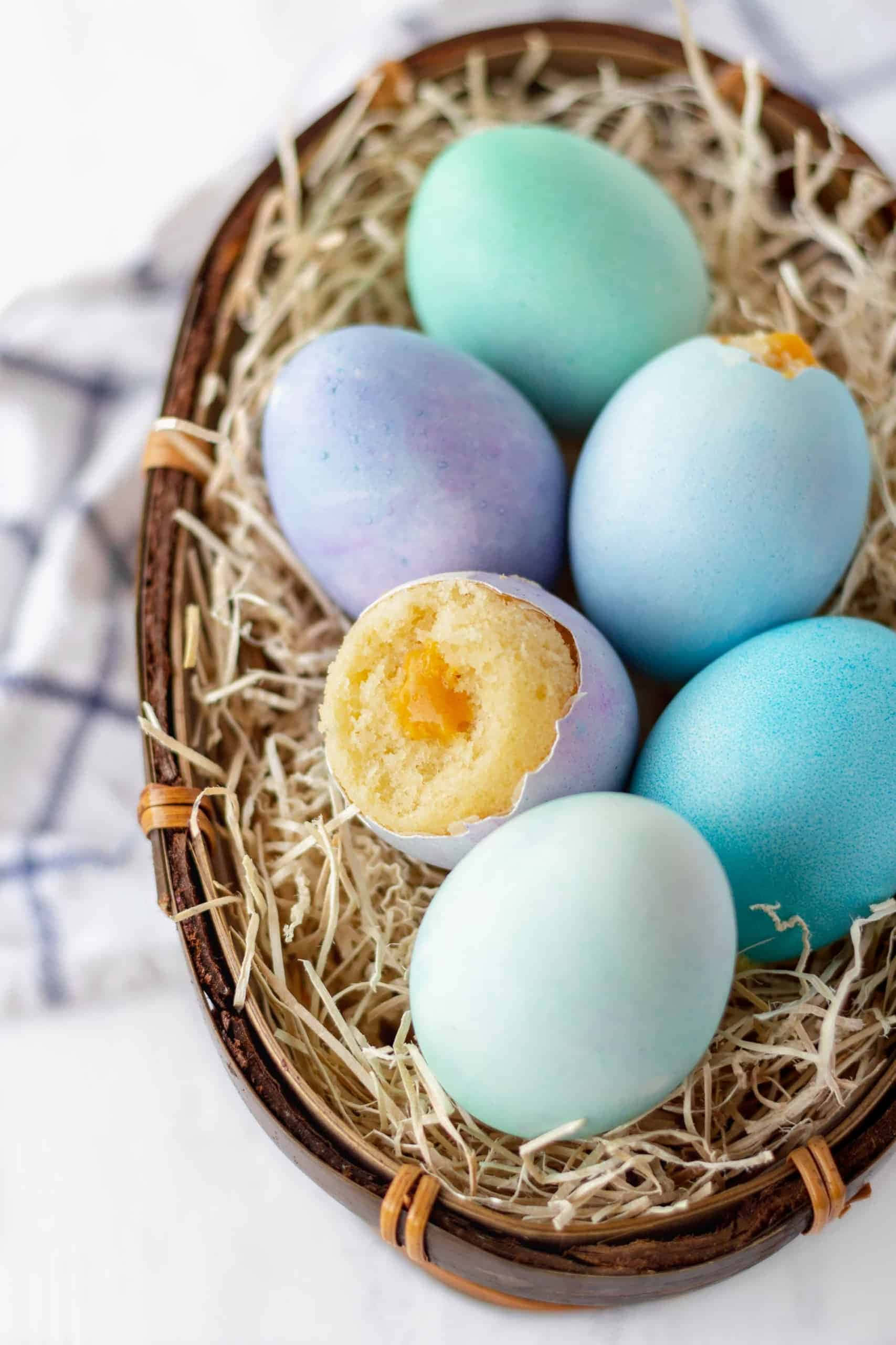 Eggshell 桌布 壁紙 — 粉藍色和紫色雞蛋放在編織籃內的稻草中，其中一個裂開露出金黃色的蛋黃。