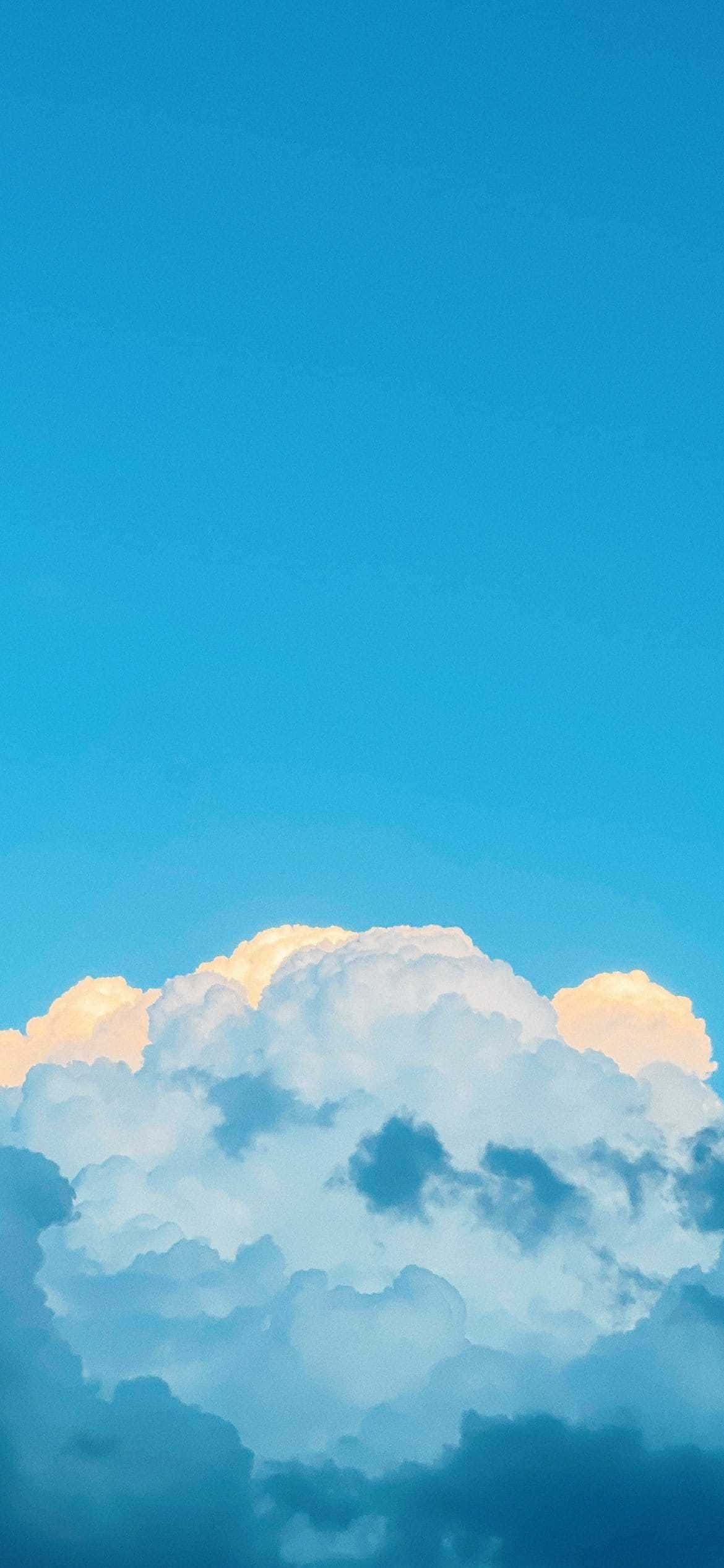 粉藍調天空雲朵壁紙 壁紙 — 廣闊的天藍色天空，蓬鬆的白雲在日落地平線上閃耀著金色光芒。