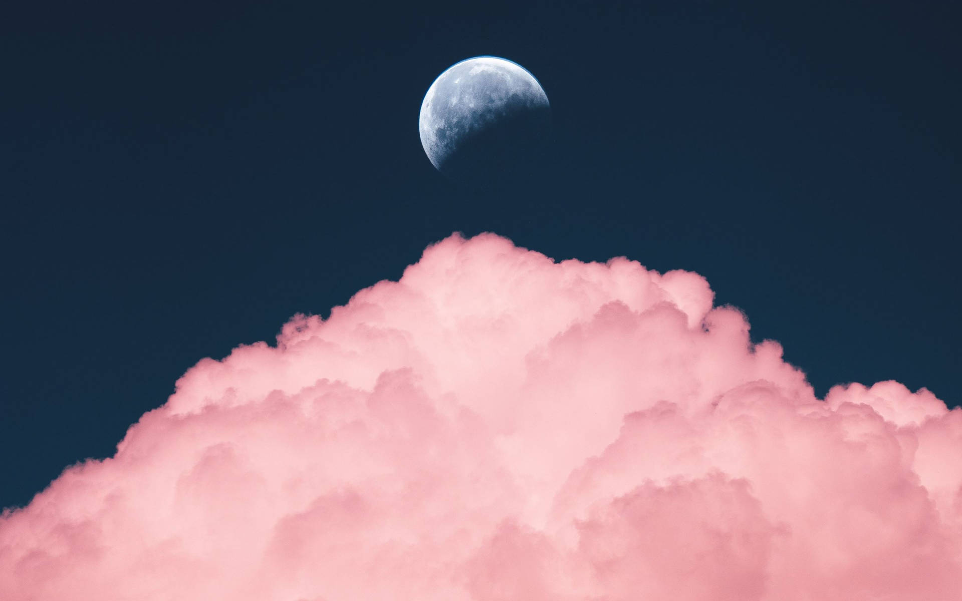 粉雲半月MacBook Pro風格 壁紙 — 一彎新月在深藍色夜空中的一朵毛茸茸粉紅雲朵上方發光。