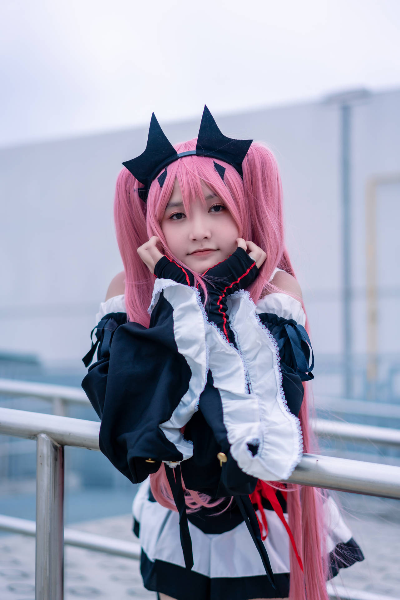 穿著女僕裝的cosplayer，粉色頭髮和貓耳，在戶外擺姿勢。