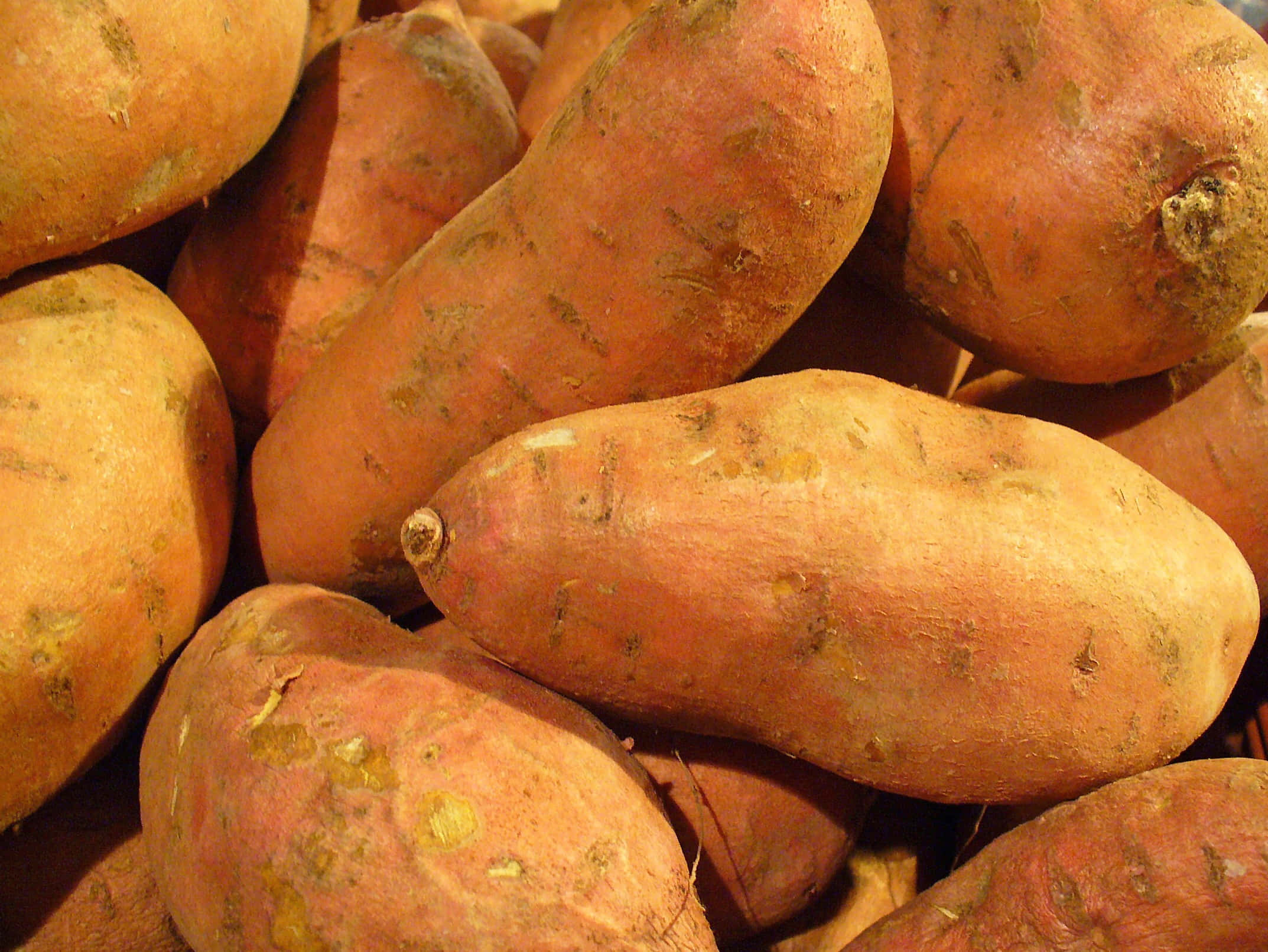 Potato 桌布 壁紙 — 粗糙外皮嘅番薯喺溫暖燈光下堆埋一齊嘅特寫。
