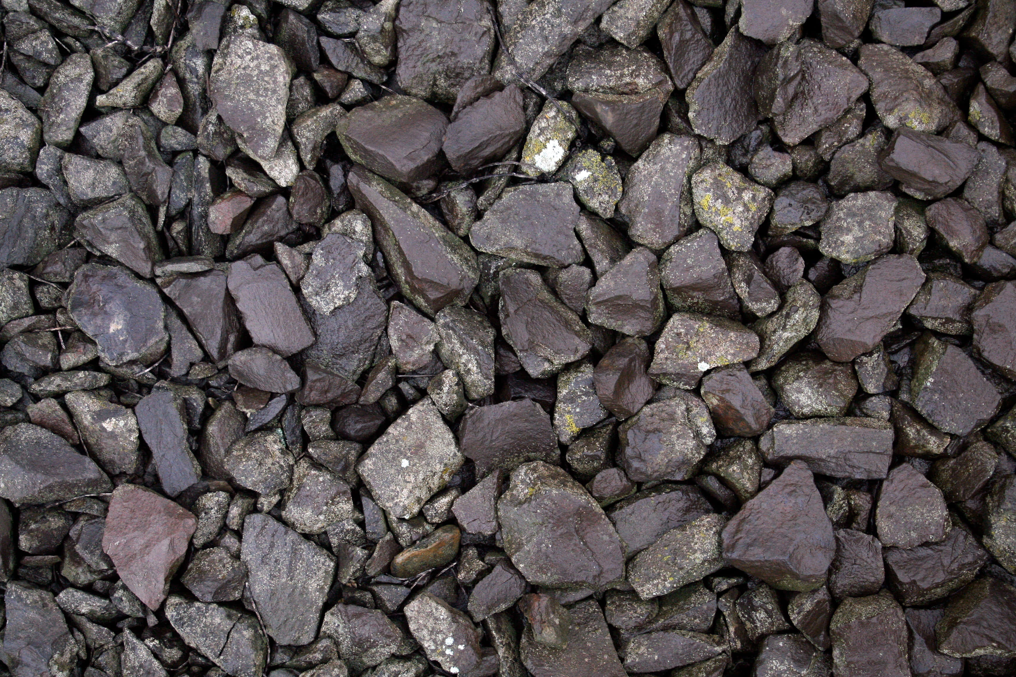 Dark Rock 桌布 壁紙 — 粗糙深灰色岩石的特寫，其鋸齒狀表面上散佈著細微的白色和黃色礦物斑點。