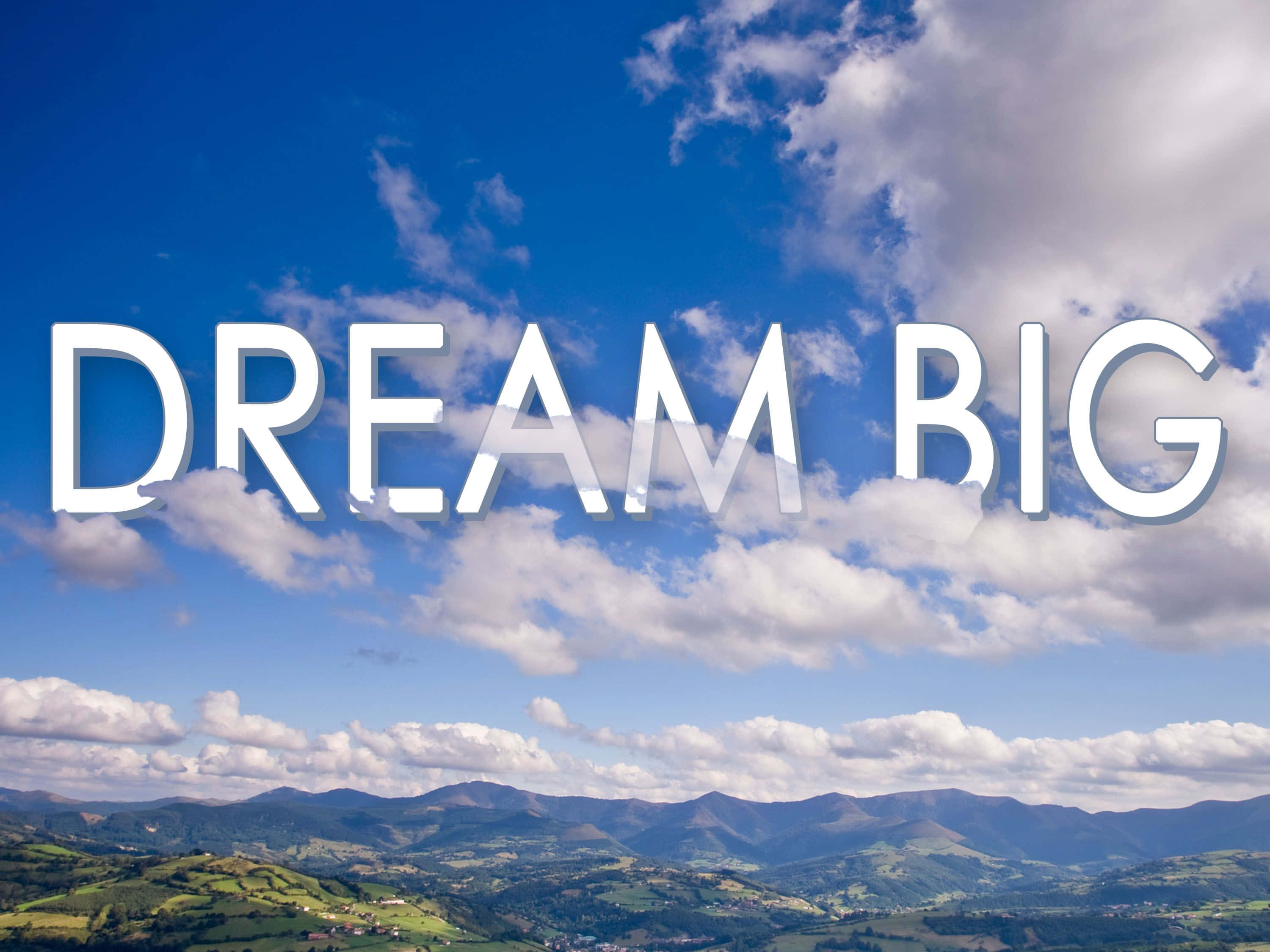 dreams 桌布 壁紙 — 粗體白色文字 'DREAM BIG' 漂浮在充滿活力的藍天上，蓬鬆的雲朵在起伏的綠色山丘和遠處的山脈之上。