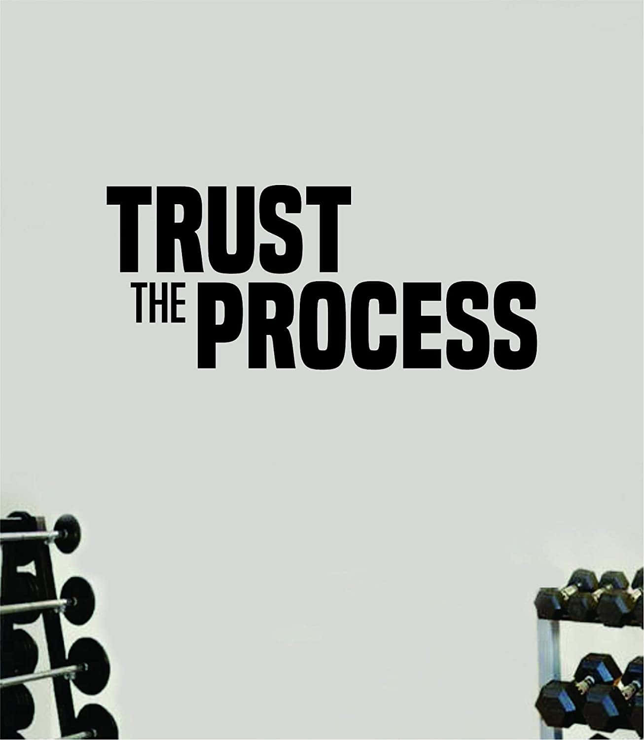 trust 桌布 壁紙 — 粗體黑色文字 'TRUST THE PROCESS' 主導了一面極簡風格的健身室牆壁，邊緣可見啞鈴架。