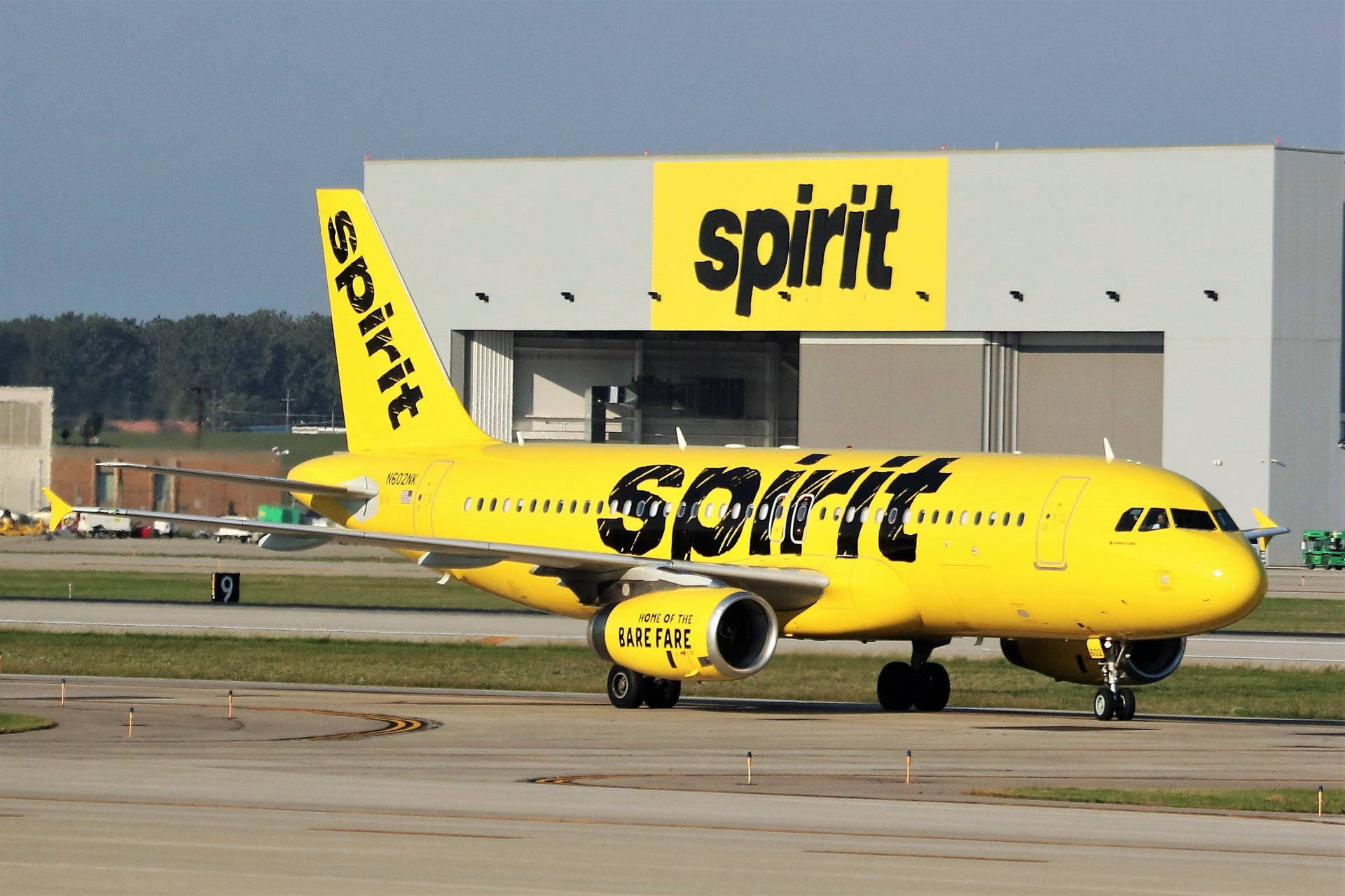 黃色Spirit Airlines飛機在機場跑道近機庫處。