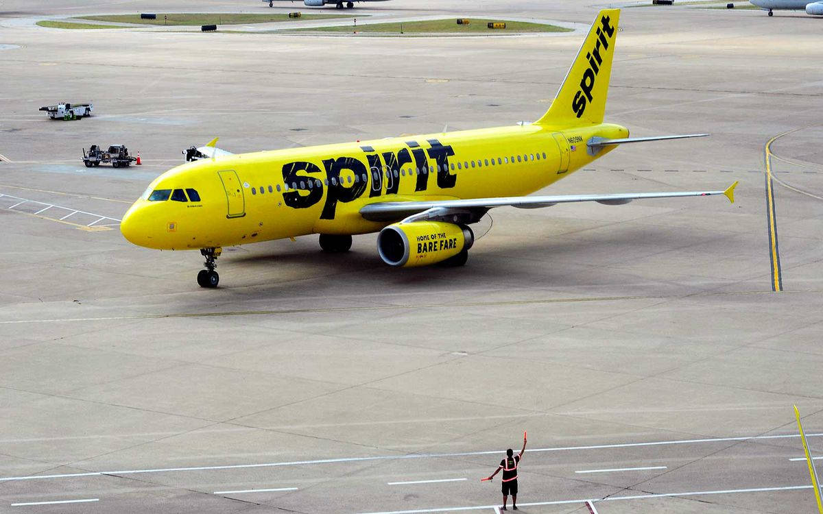 黃色精神航空飛機在機場停機坪被地勤人員指揮。