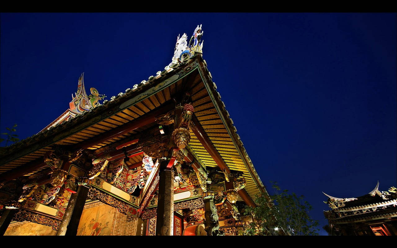 在深藍色天空背景下，夜間照亮的華麗寺廟屋頂。