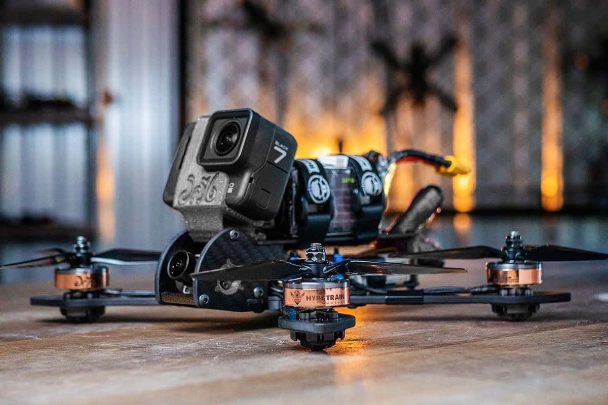 精緻無人機帶來獨特空中視角 壁紙 — 一架黑色競速無人機裝有GoPro 7相機，放置在溫暖照明的工業空間的木地板上。