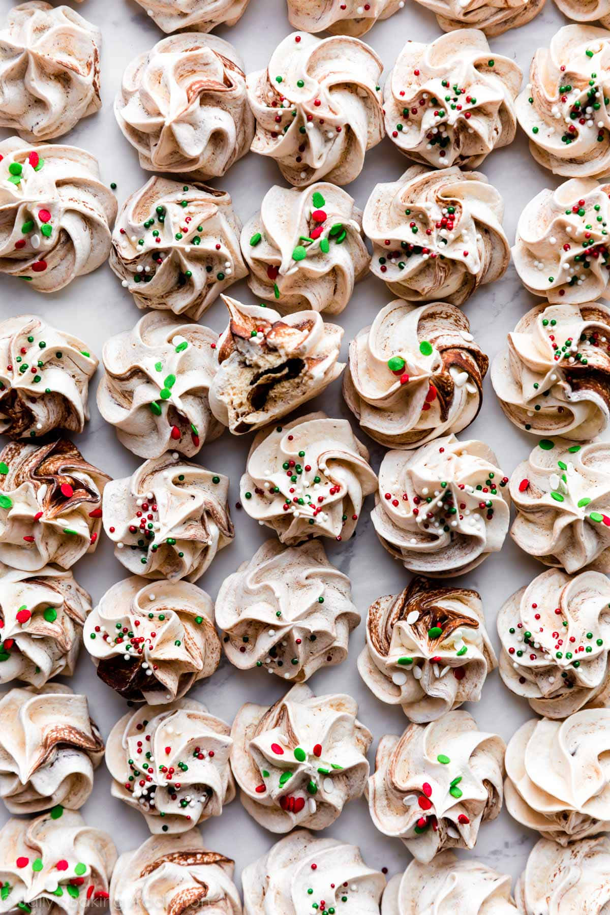 Meringue 桌布 壁紙 — 精緻的漩渦蛋白酥，飾有節日紅綠糖粒和朱古力漩渦，整齊排列在大理石表面上。