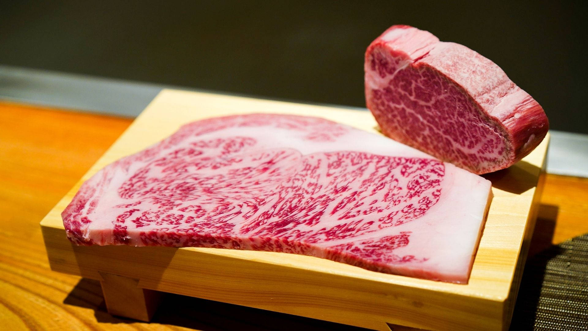 兩塊高品質的大理石紋牛肉展示在木板上。