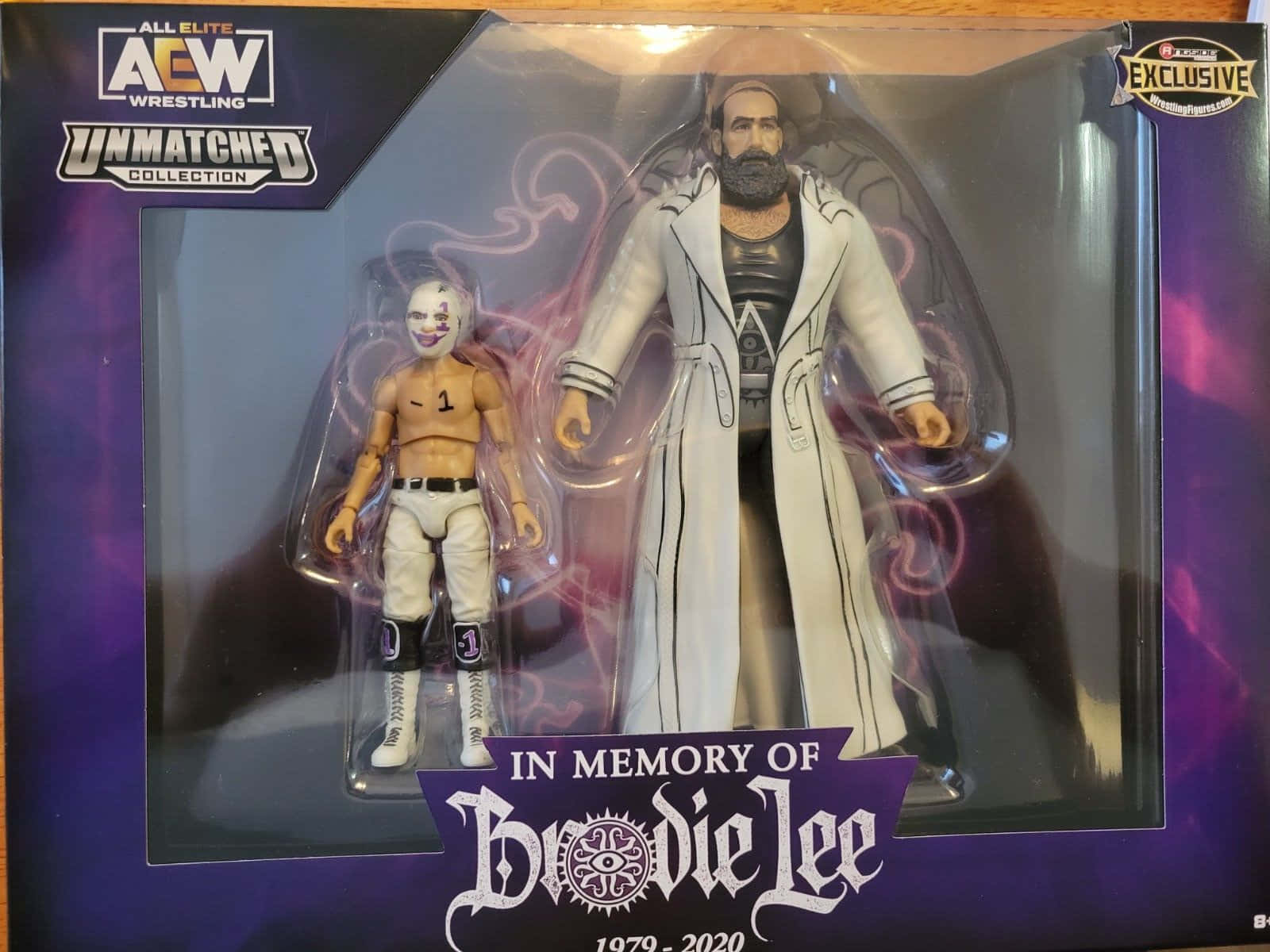 紀念Brodie Lee玩具收藏 壁紙 — 兩個包裝中的AEW摔角動作人偶，一個有白色臉部彩繪，另一個穿著帶有紫色漩渦的白色外套。