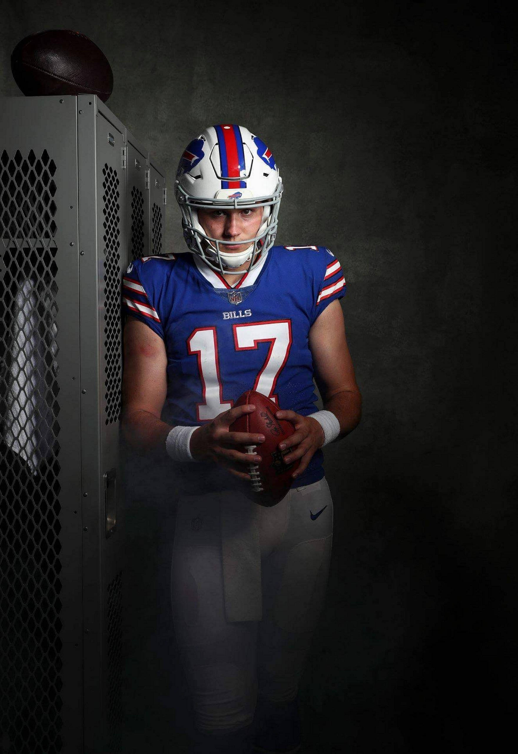 約什·艾倫NFL新秀 壁紙 — 一位身穿17號球衣的水牛城比爾隊美式足球員，在煙霧瀰漫的更衣室中，專注地抱著一個足球。