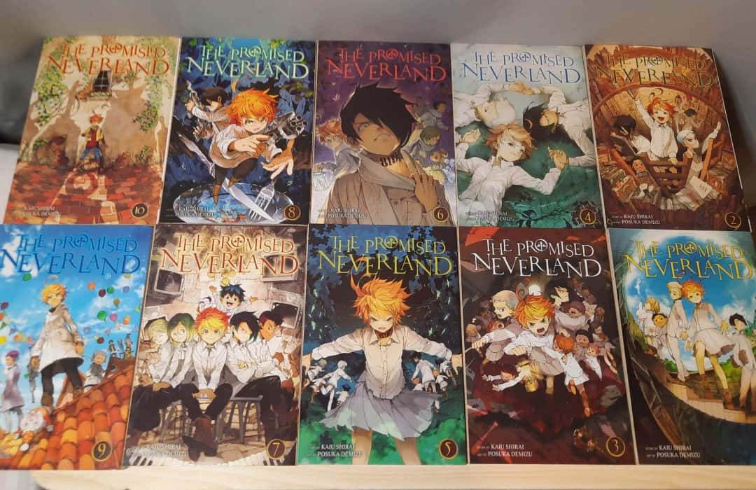 《約定的夢幻島》不同版本圖 壁紙 — 十本色彩繽紛的《約定的夢幻島》漫畫整齊排列在書架上，展示充滿活力的封面藝術，帶有動漫角色。